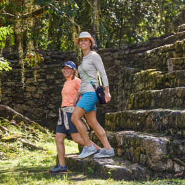 A couple of women walk down some old Mexican ruins.