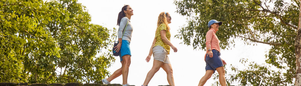 Three women hike across a wooden bridge