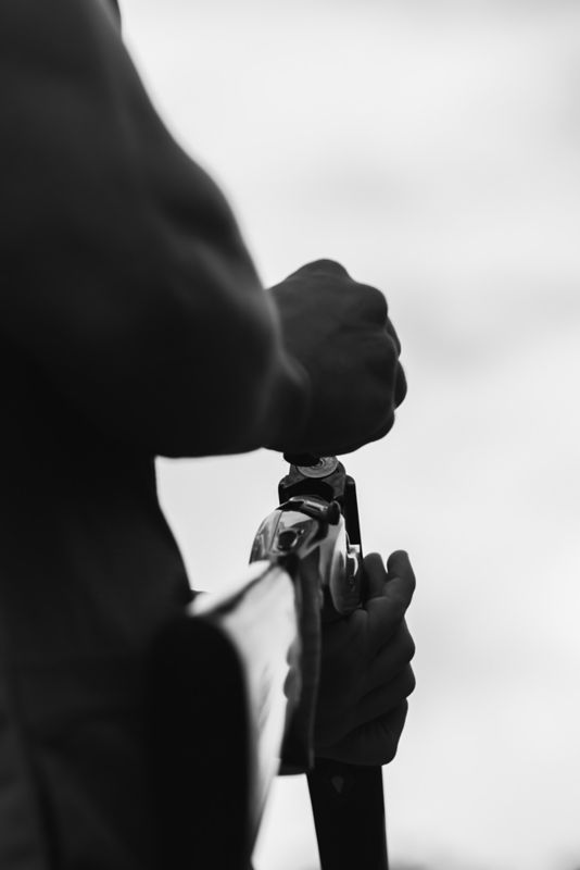 A black and white image of a person loading a shotgun.