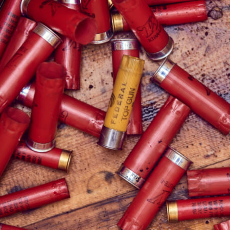 Red and yellow shotgun shells piled on a wood table