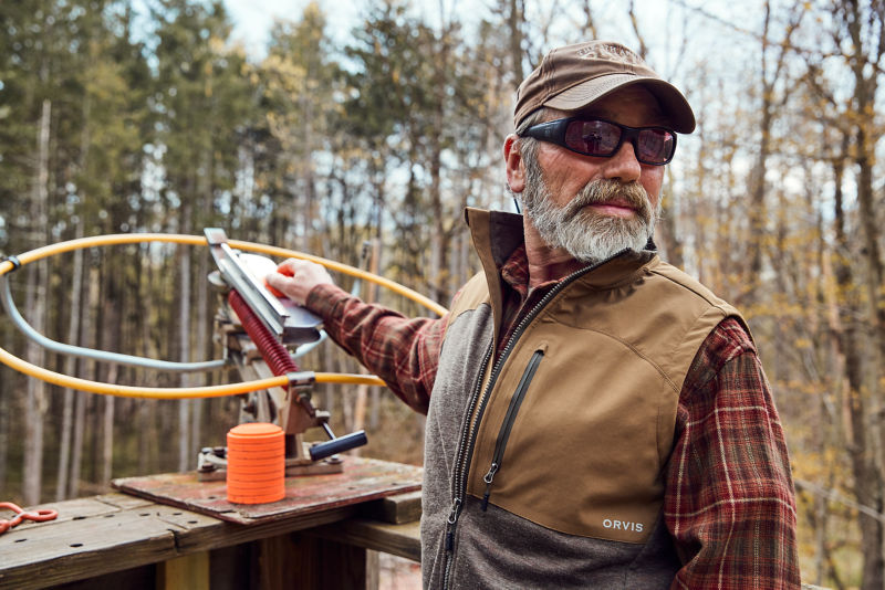 A man wearing a hat with a white beard loading a clay shooter.