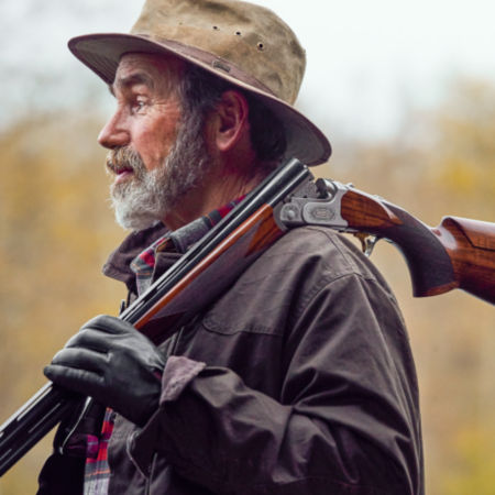 A broken open shotgun slung over a hunter's shoulder