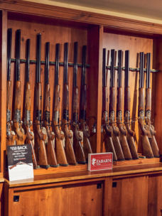 A wooden rack of shotguns line the wall of Orvis's Sandanona Shooting Grounds.
