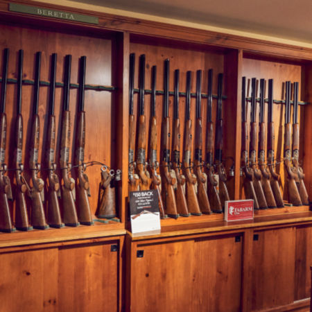 A wall of wooden racks filled with shotguns standing on their butts