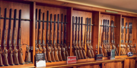 A wooden racks of shotguns line the wall of Orvis's Sandanona Shooting Grounds.