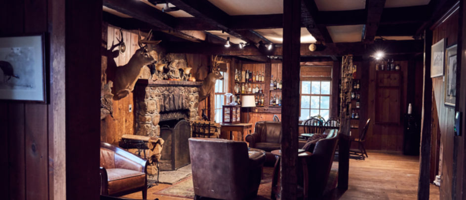 A fireplace and chairs inside Orvis' Sandanona Lodge