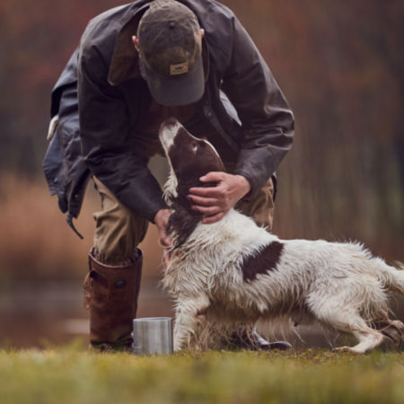 A man hugging his wet hunting dog.