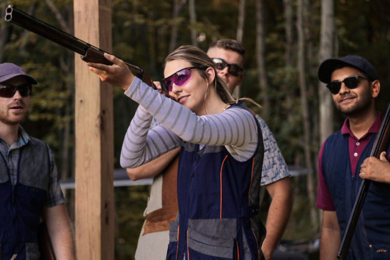 A woman aims her shotgun from a clays stand