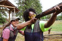 female instructor stands behind another woman shooting