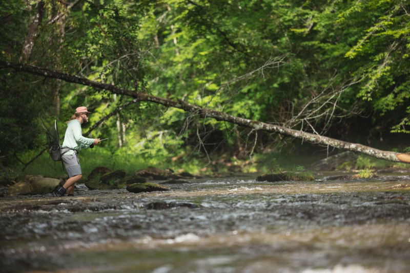 An angler walks through the fast water with his gear.