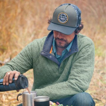 Man in an Eucalyptus Outdoor Quilted Snap Sweatshirt makes coffee by a fire.