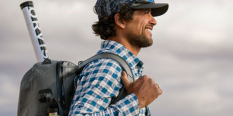 A smiling man wearing a loaded fishing backpack