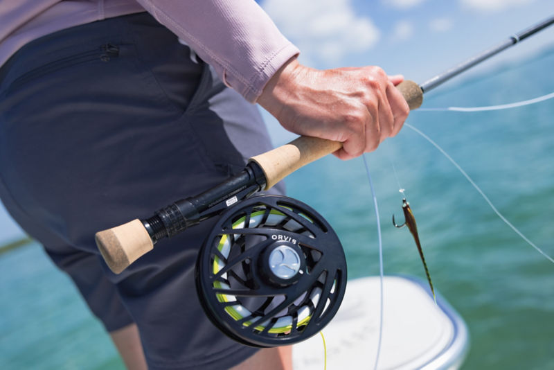 A close-up on a fly reel in use on a skiff in saltwater.