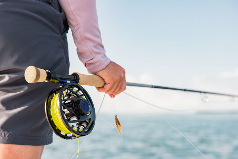 An angler carries her rod and reel to the ocean.