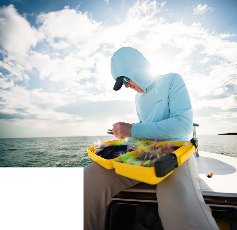 A close up on a man wearing a UPF protective shirt and picking through his fly box.