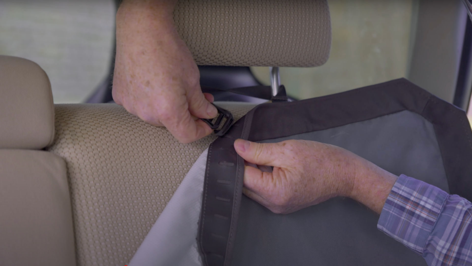 A man installing an Orvis Tough Trail® Grip-Tight® Backseat Protector.
