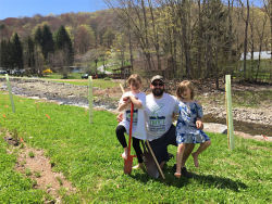 A father and his two daughters standing next to a stream