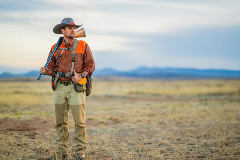 A hunter in a midweight shooting shirt looks out onto the plains.