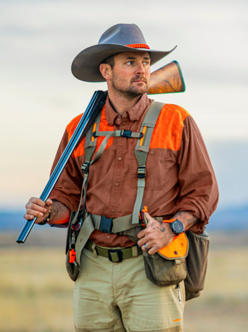 A hunter in a midweight shooting shirt looks out onto the plains.