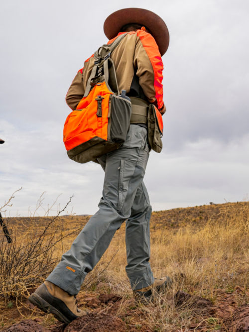 A hunter in Upland Hunting Softshell Pants walks uphill towards a truck.