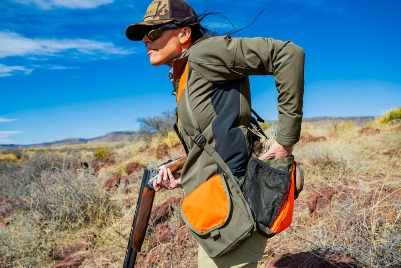 Hunter places quail inside her hunting vest.