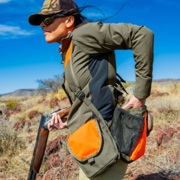 A hunter reaches into her vest for a shell.