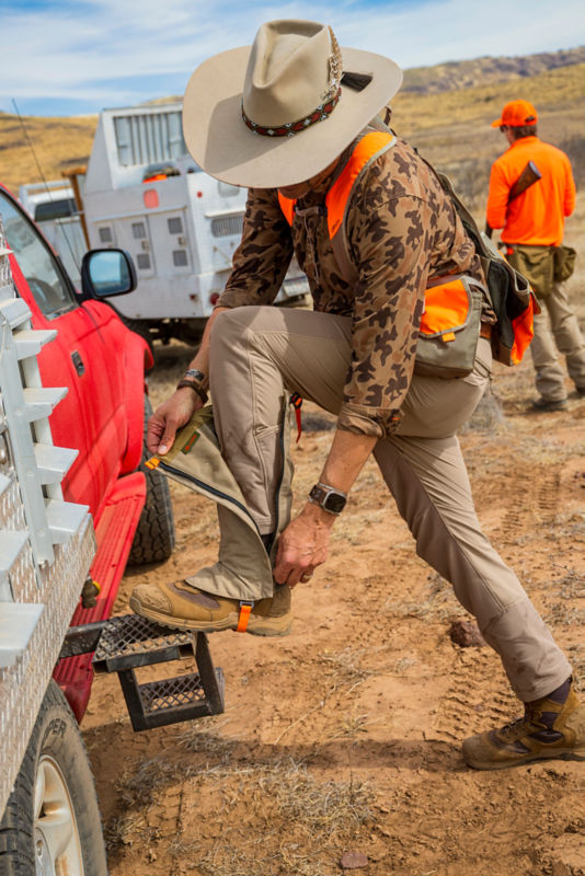 Hunter in Midweight shooting shirt zips up gaiters onto his boots.