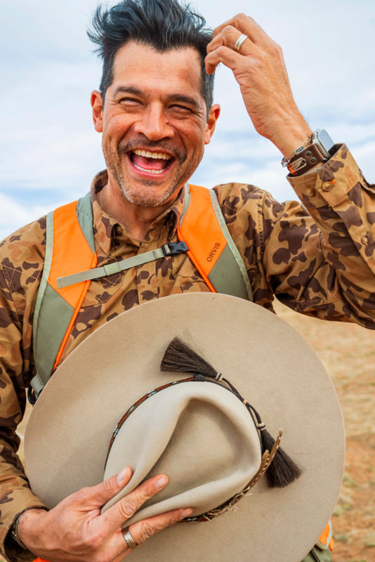 A hunter caught mid-laugh while removing his hat.