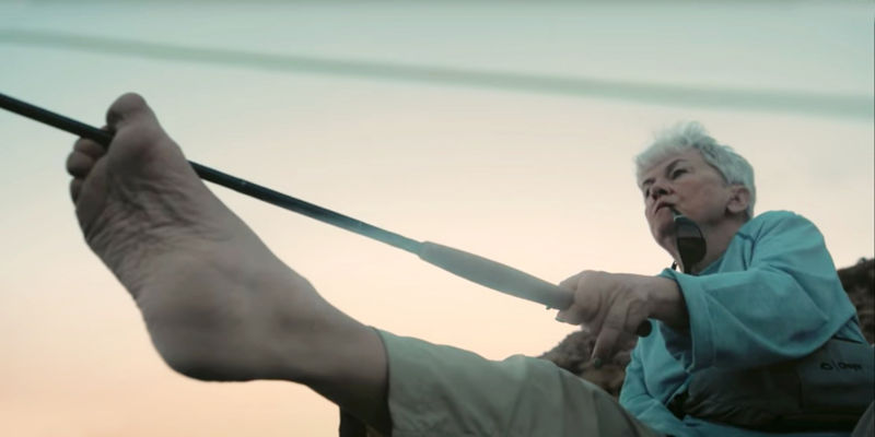 An image of Marty Loudder holding a fly rod with her foot.