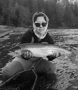 Black and white photo of Tracy Nguyen-Chung holding a fish in the water