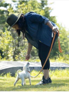 A woman bending down to giver her leashed puppy a treat