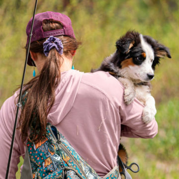 An angler carries her dog.