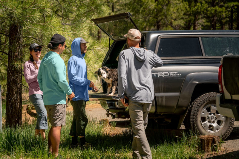 Four anglers gathered around a car with a dog standing in the back