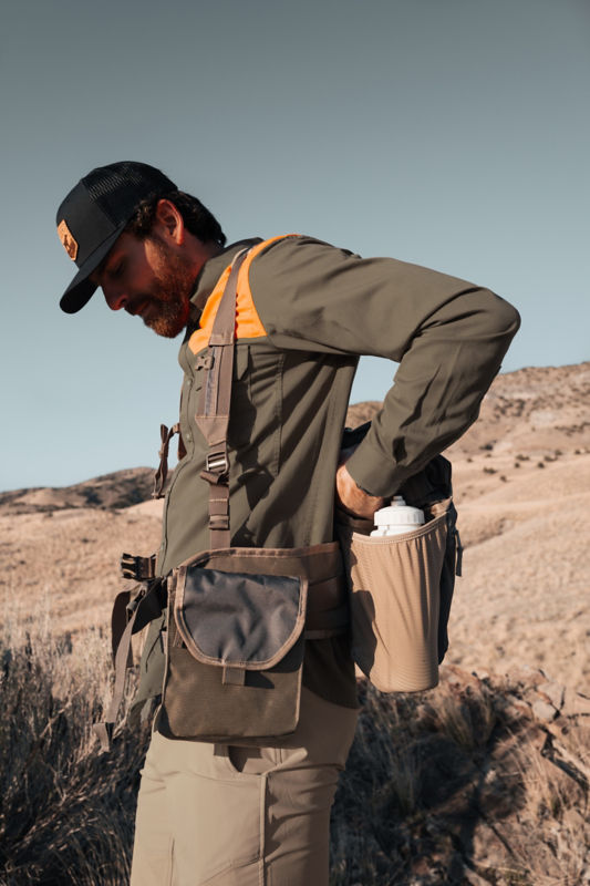A hunter pauses to access the back pocket of his hunting vest.