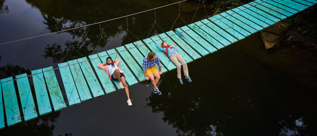 Three people relaxing on a wooden bridge in Belize