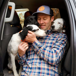 Simon Perkins cuddling with his dogs inside a vehicle.