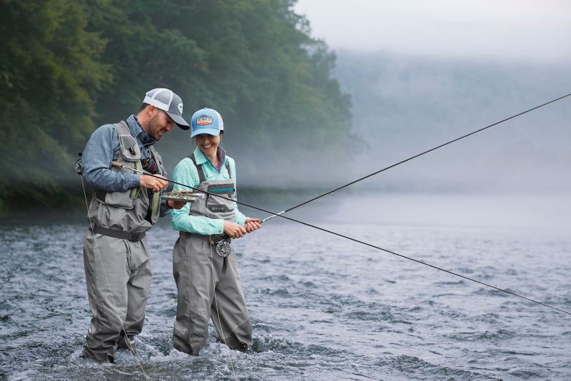 A guide helping a client choose the right fly while standing in a shallow river.
