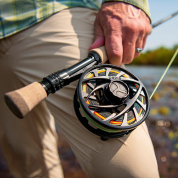 Man wades upstream with rod and Mirage LT reel.