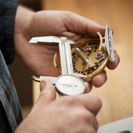 An Orvis associate measured a reel with calipers