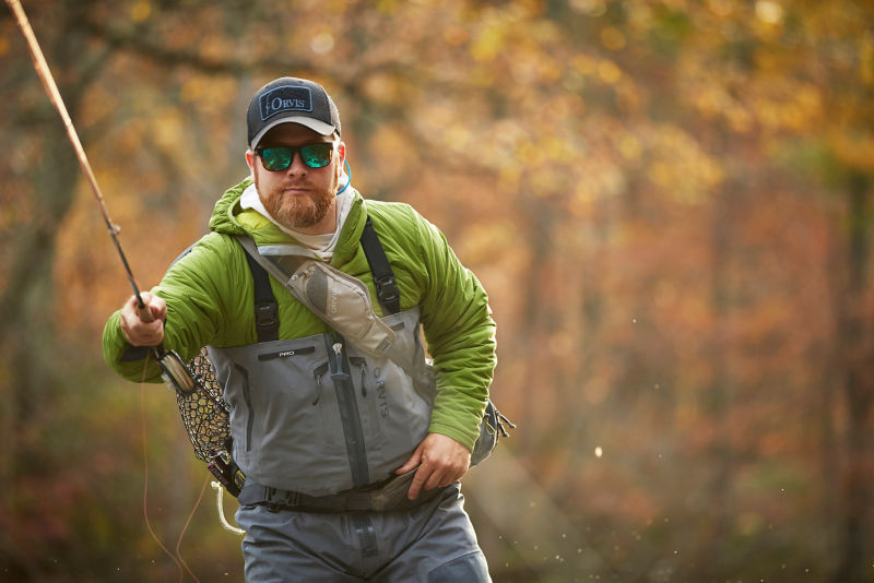 An angler leans into his cast on an autumn day.