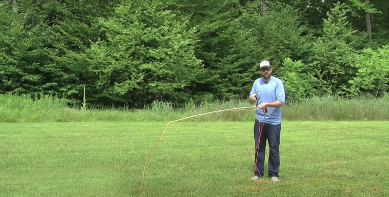 An instructor standing on grassy lawn holding a fly rod