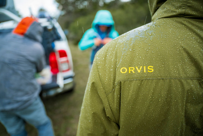 A close-up image of water beading up on the shoulder of a green PRO jacket