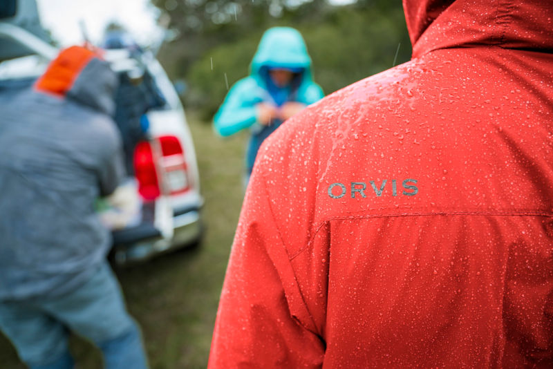 A close-up image of water beading up on the shoulder of a lava-colored PRO jacket