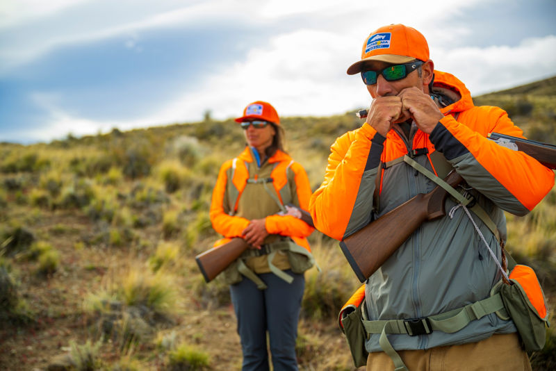 Hunters in bright orange gear looking over an upland landscape
