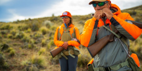 Hunters in bright orange gear looking over an upland landscape