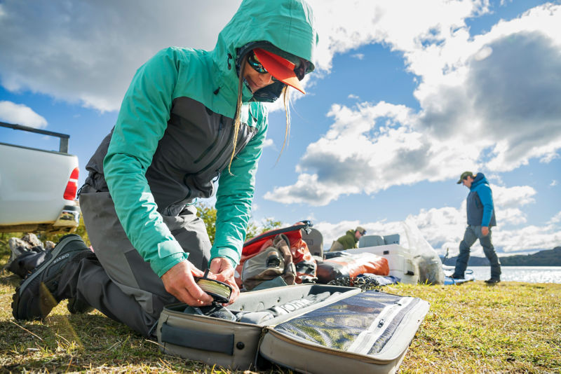 An angler sorts through her carry-it-all bag for fishing tools.