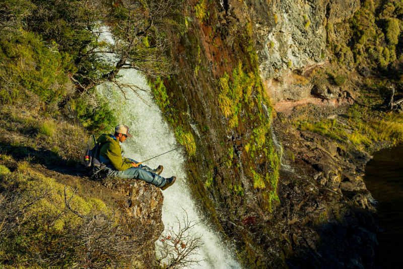Several wooden chairs on a sandy beach looking out over a sunrise.