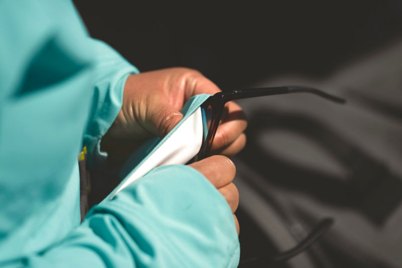 An angler cleans their sunglasses with the chamois material on their shirt