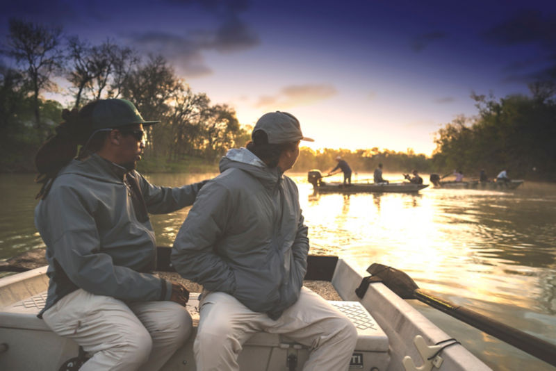 Two people in a boat watching another boat full of anglers.