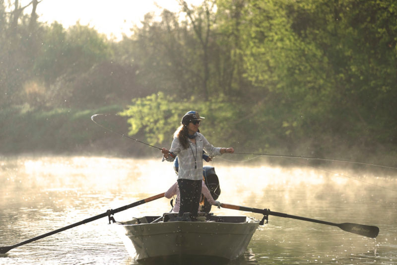 An angler, standing in a boat, casting